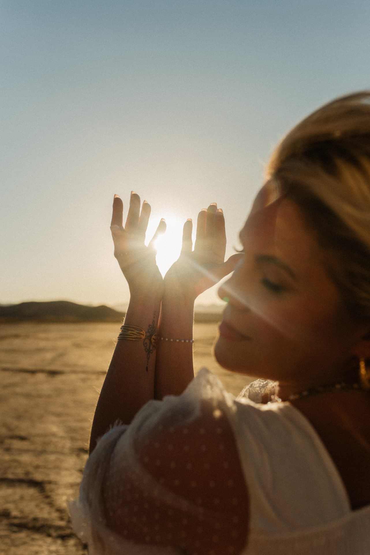 Nina Moon in the desert at golden hour, holding the sun between her hands